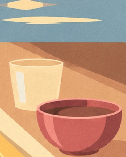 The red bowl and pale yellow glass on the sunlit table in front of the sea
