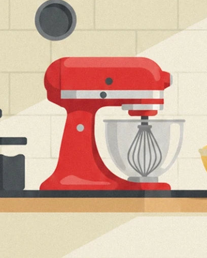 A red stand mixer with its whisk and bowl in front of a tiled wall