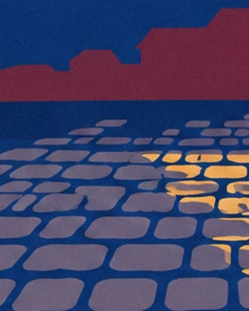 The blue-tinged cobblestones of the street at night, lit by golden reflections