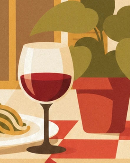 Un verre de vin rouge devant une plante aux feuilles vertes dans un pot rouge