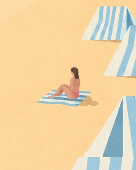 A woman sitting on her blue and white striped towel, between the beach huts