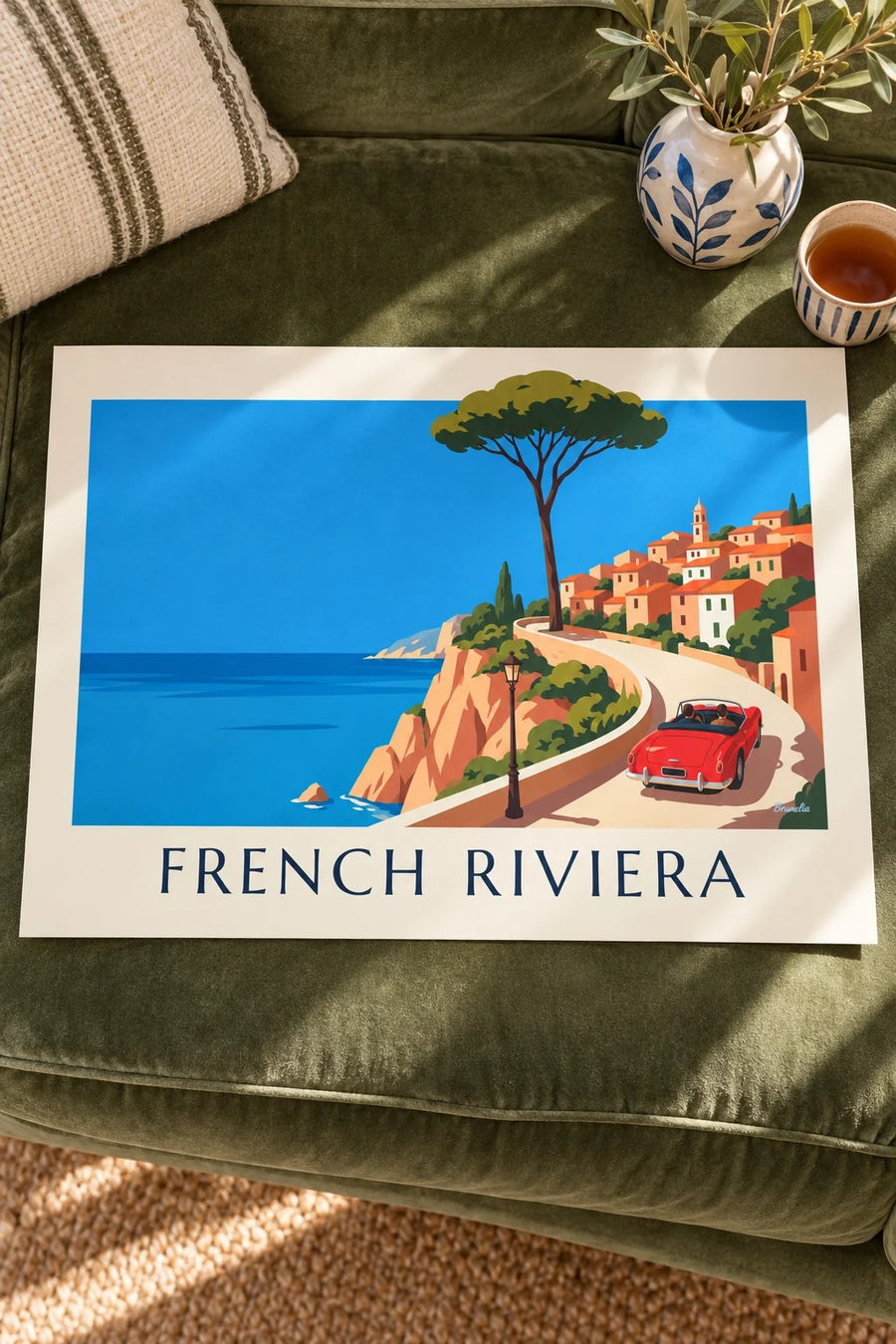Red convertible on a French Riviera coast road poster: laid flat on a table